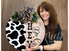 a woman holding up a cow print sign