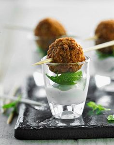 small appetizers with toothpicks in glass cups on black slate serving tray