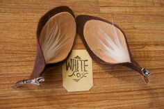 two brown and white feathered spoons sitting on top of a wooden table next to a tag