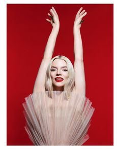 a woman with her arms in the air, wearing a white dress and red lipstick