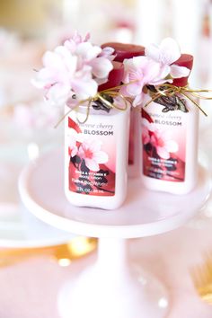 two bottles of body lotion sitting on top of a white plate with pink flowers