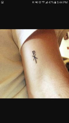 a person with a small tattoo on their arm that has a cross and an arrow