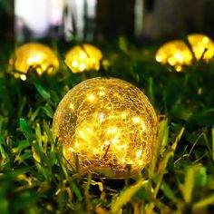 some yellow lights that are on the grass in the night light up ball ornament