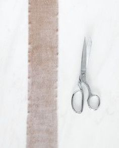 a pair of scissors sitting on top of a table next to a piece of fabric