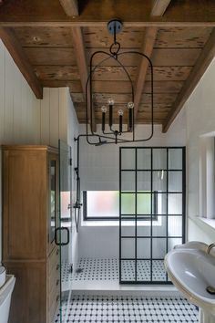 a bathroom with black and white tile flooring next to a bathtub under a wooden ceiling