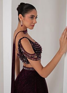 This stunning Black Platinoir Crepe Embellished Lehenga Set exudes modern elegance and glamour. Crafted from luxurious platinoir crepe, the black lehenga features a dramatic full-length skirt with all-over metallic brazen fall detailing, adding a shimmering effect with every movement. The crystal-embroidered waistband accentuates the waist, offering a refined silhouette. Teamed with a cold shoulder blouse, the ensemble reaches new heights with its halo crystal tassel embellishments, delivering a unique and stylish twist. The look is completed with a choker-style embellished dupatta, perfectly complementing the outfit with a sophisticated touch. Ideal for Cocktail parties, Sangeet nights, or evening events, this lehenga set is designed for those who wish to make a bold and fashionable state Embellished Lehenga, Black Lehenga, Embroidered Lehenga, Indian Wedding Wear, Full Length Skirts, Cocktail Parties, Cold Shoulder Blouse, Choker Style, Wedding Wear