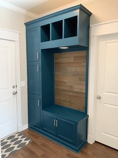 an empty room with a large blue cabinet and wooden flooring in front of the door