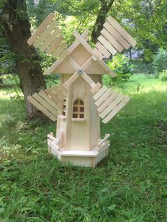 a wooden wind mill sitting in the grass