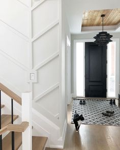 a black and white cat is walking down the stairs in a house with wood floors