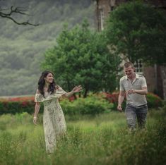 a man and woman are walking through the grass