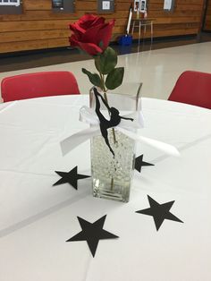 a vase with a single rose in it sitting on a table at a school banquet