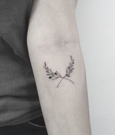 a woman's arm with a small branch tattoo on the left side of her arm