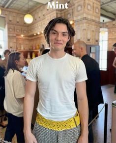 a young man standing in front of a counter with his hands on his hips and looking at the camera