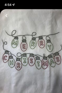 embroidered christmas lightbulbs and merry lights on a white linen pillow cover with red, green and blue thread