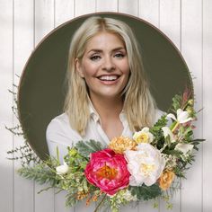 a woman holding a bouquet of flowers in front of a white wall with wood paneling