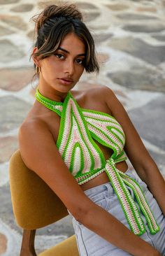 a woman sitting in a chair wearing a green and white top