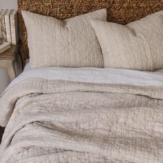 a bed with two pillows on top of it next to a night stand and table