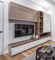 a modern living room with white walls and wood flooring, built - in entertainment center