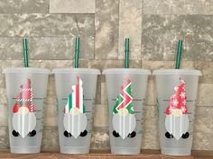 four plastic cups with santa hats on them are lined up against a wall and decorated with green straws