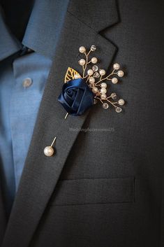 a man in a suit with a blue lapel flower and pearl pins on his lapel