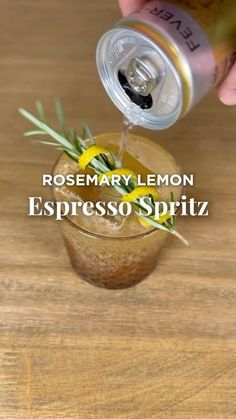 a person pouring lemonade into a glass with rosemary spritz in it on top of a wooden table