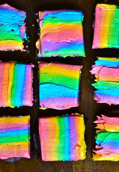 there are several pieces of cake with rainbow frosting on it and one is cut into squares