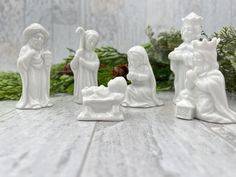 white ceramic nativity figurines sitting on top of a wooden table