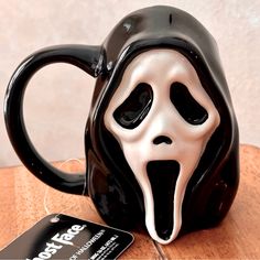 a black and white ceramic coffee mug with a ghost face on it's side