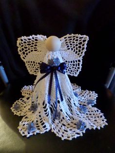 an angel made out of crochet with blue ribbon and bow sitting on top of a table