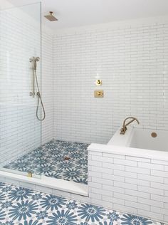 a bathroom with blue and white tiles on the floor, shower stall and bathtub