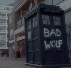 a blue tardish with the words bad wolf written on it in front of some buildings