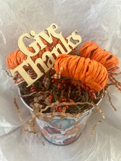 a bucket filled with orange yarn and some wooden words that say give thanks on it