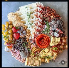 a platter filled with cheese, crackers, fruit and nuts on top of a table