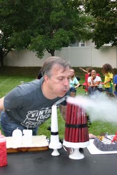 a man is blowing out water on a table with other people in the back ground