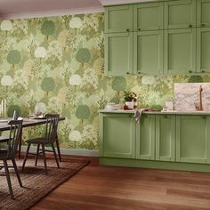 a kitchen with green cupboards and wallpaper on the walls, along with a dining room table