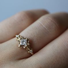 a person's hand with a gold ring on top of it and a diamond in the middle