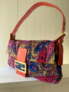 Orange and multicolor embroidered Fendi Paisley Baguette with gold tone hardware, leather trim and flat shoulder strap. Satin lining with flat pocket at interior and magnetic closure at front. Very good condition: Dior Shoes, Chanel Handbags, Leather Trim, Magnetic Closure, Leather Trims, Paisley, Fendi, Shoulder Strap, Gold Tones