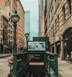 a city street with tall buildings and lots of green traffic signs on the sides of it