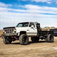 a white truck parked in the middle of a dirt field