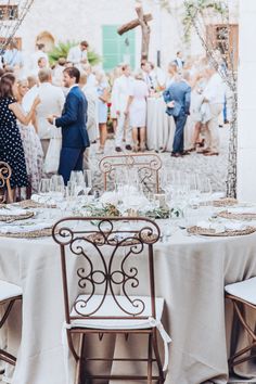 a group of people standing around a table with white clothed tables and chairs in front of them