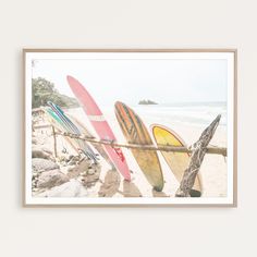 there are surfboards leaning up against a fence on the beach by the water's edge