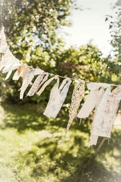 some paper towels hanging from a clothes line in the grass with trees in the background