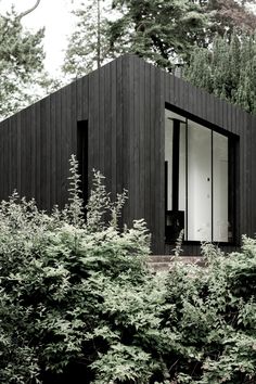 a black house surrounded by trees and bushes