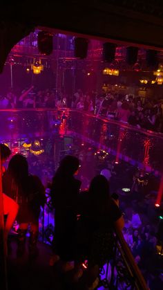 a group of people sitting at tables in a room with purple lights on the walls