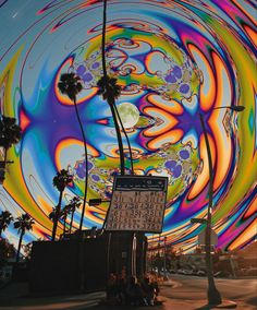 an abstract painting on the side of a building with palm trees in front of it