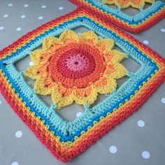 two crocheted squares are sitting on a table with polka dotty cloths