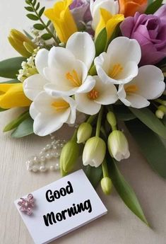 a bouquet of flowers sitting on top of a table next to a card that says good morning