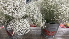 two buckets filled with baby's breath flowers on top of a wooden table