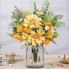 a glass vase filled with yellow flowers on top of a table next to candles and other items