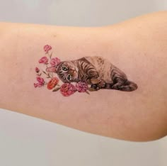 a cat laying on its side with flowers around it